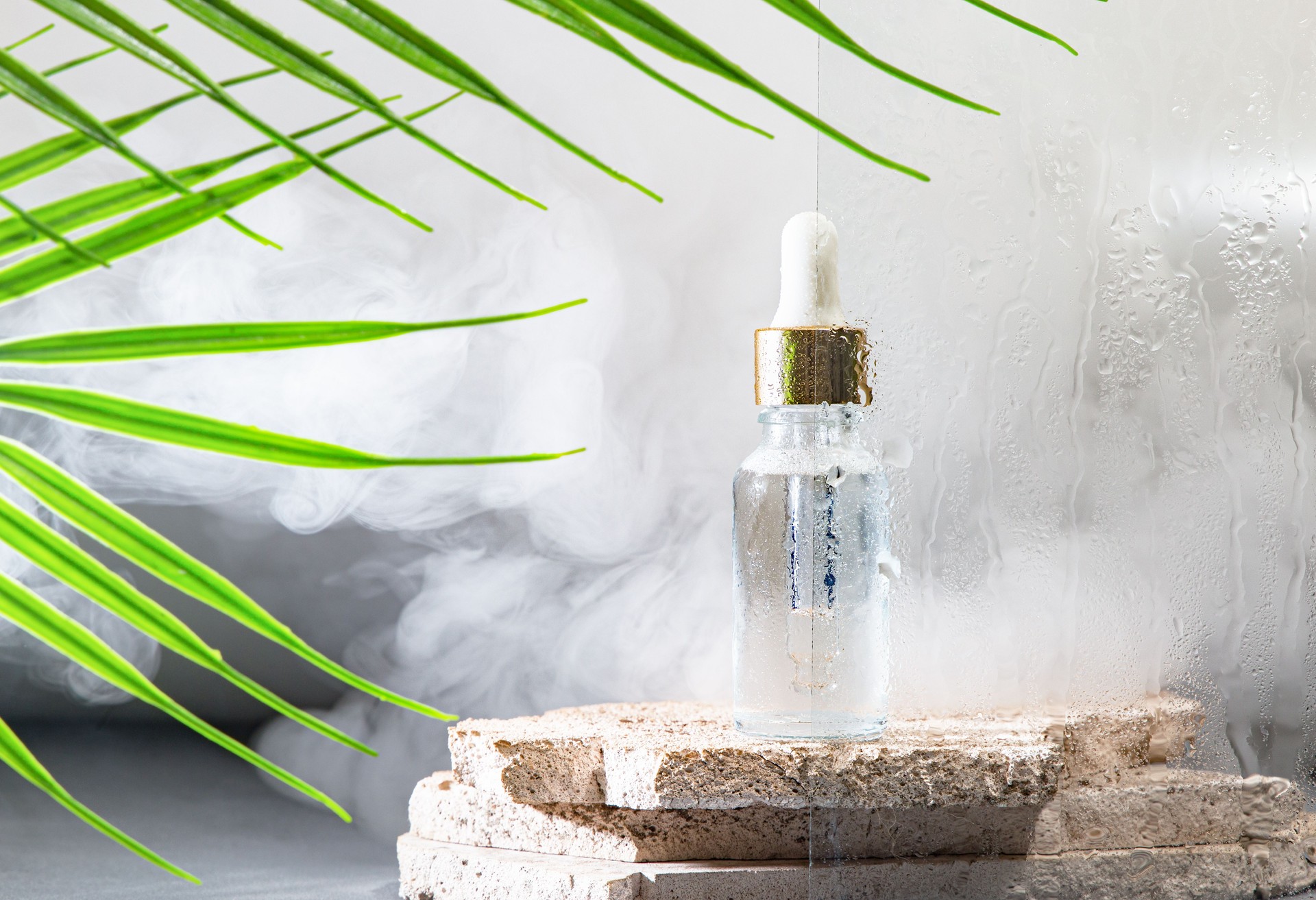 Face serum in a glass bottle against a background of smoke with water drops. Moisturizer & Rejuvenator for all ages